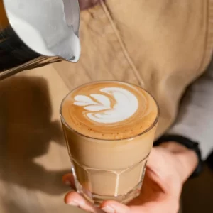 female barista with apron decorating coffee glass with milk 23 2148824457 female-barista-with-apron-decorating-coffee-glass-with-milk_23-2148824457